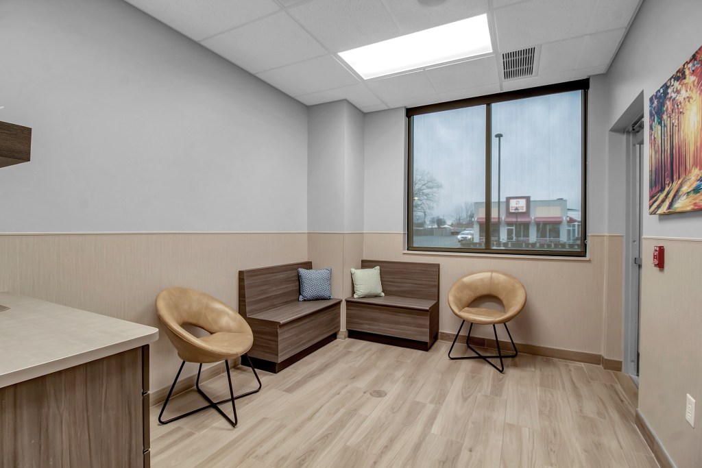 Exam rooms include built-in seating, black windows, and luxury vinyl flooring.